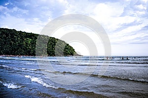 Cove with sunbathers and tourists on the beach on beautiful picturesque day with mountains