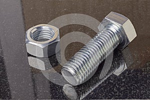 Cover the bolt and nut with galvanization. A polished stone of dark color lies on a piece. Close-up