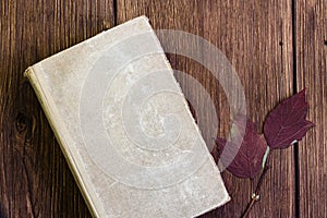 Cover of closed old shabby book with blank sheets of vintage paper on a wooden background in rustic style