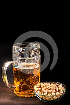 Cover page with traditional Octoberfest Bavarian beer in a big one liter mug half drunk with wet walls and pistachios, Germany, at