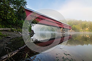 Covered bridge over river with reflection in the mist