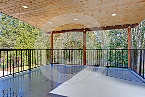 Covered deck with wooden ceiling and iron handrails. photo