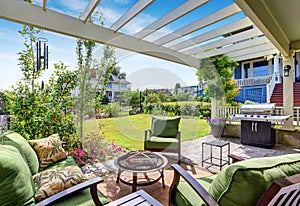 Covered patio area with outside chairs in the backyard garden. House exterior.