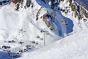 Covered with snow Aibga cirque ski slopes and chair ski lifts in Gorky Gorod winter mountain resort. Skiers ride on ski lifts on s