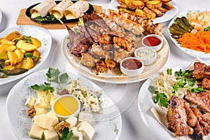 A covered table with many different dinner dishes. Lots of food on a white isolated background