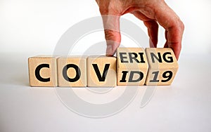 Covering covid-19. Male hand turns cubes with words `covering covid19`. Covid-19 postpandemic concept. Beautiful white backgroun