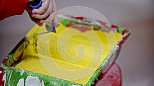 Covering a roller in yellow paint in the paint tray