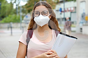 COVID-19 Beautiful student female with protective mask walking in city street. College young woman back to school after pandemic