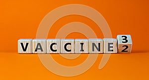 Covid-19 booster vaccine shot symbol. Turned a wooden cube and changed words `vaccine 2` to `vaccine 3`. Beautiful orange
