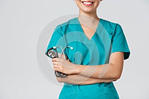 Covid-19, coronavirus disease, healthcare workers concept. Cropped shot of asian female doctor body smiling, cross arms