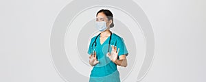 Covid-19, coronavirus disease, healthcare workers concept. Displeased asian female doctor, physician or nurse avoiding