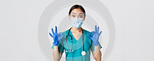 Covid-19, coronavirus disease, healthcare workers concept. Excited and impressed asian doctor, nurse in medical mask and