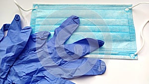 COVID-19. Coronavirus. Medical latex gloves and protective blue surgical mask on a white background. Biohazard protection Close-up