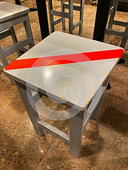 Covid 19 Coronavirus Social Distancing Stool Chair with a Red Tape over the Top