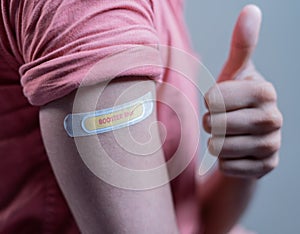 Covid-19 or coronavirus vaccinated shoulder with booster shot sticker and thumbs up gesture - concept of approved coronavirus 3rd