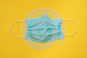 COVID-19 disposable surgical face mask on yellow background