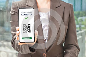 Covid-19 health pass app concept on smart phone. Woman hodling phone. QR code for verification of immunization after vaccination