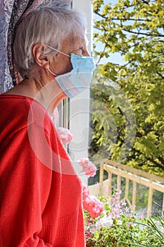 The Covid-19, health, safety and pandemic concept - senior old lonely woman near the window