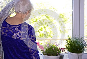 The Covid-19, health, safety and pandemic concept - senior old lonely woman near the window