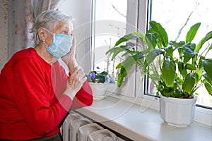 The Covid-19, health, safety and pandemic concept - senior old lonely woman sitting near the window