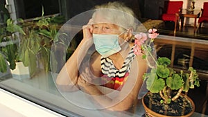 The Covid-19, health, safety and pandemic concept - senior old lonely woman sitting near the window