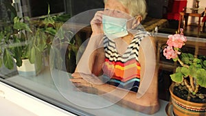 The Covid-19, health, safety and pandemic concept - senior old lonely woman sitting near the window