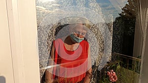 The Covid-19, health, safety and pandemic concept - senior old lonely woman sitting near the window