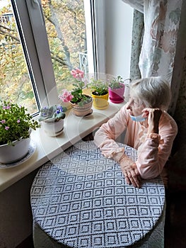 The Covid-19, health, safety and pandemic concept - senior old lonely woman sitting near the window