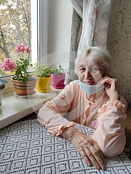 The Covid-19, health, safety and pandemic concept - senior old lonely woman sitting near the window