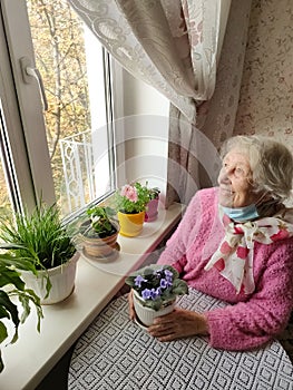 The Covid-19, health, safety and pandemic concept - senior old lonely woman sitting near the window