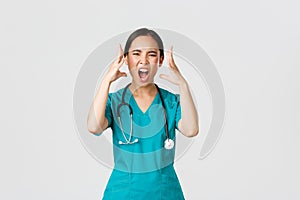 Covid-19, healthcare workers and preventing virus concept. Annoyed and angry, pissed-off asian doctor, female nurse in