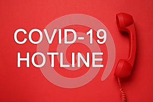 Covid-19 Hotline. Handset and text on red background, top view