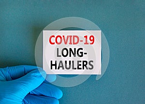 COVID-19 long-haulers covid symptoms symbol. White card with words Covid-19 long-haulers. Doctor hand, blue background, copy space