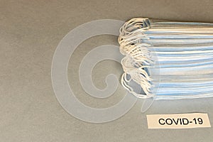 COVID-19. A lot of disposable protective masks on a gray background. The concept of vaccination and protection against coronavirus