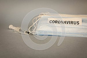 COVID-19. A lot of disposable protective masks and a syringe on a gray background. Selective focus
