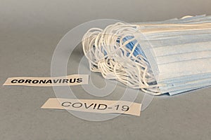 COVID-19. A lot of disposable protective masks and a syringe on a gray background. Selective focus