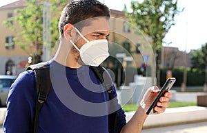 COVID-19 Mobile Application Young Man Wearing KN95 FFP2 Mask Using Smart Phone App in City Street to Aid Contact Tracing and Self