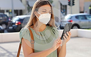 COVID-19 Mobile Application Young Woman Wearing KN95 FFP2 Mask Using Smart Phone App in City Street to Aid Contact Tracing and