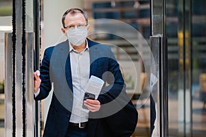 Covid-19, pandemic coronavirus concept. Office worker leaves work, wears medical face mask for infectious disease spread, dressed