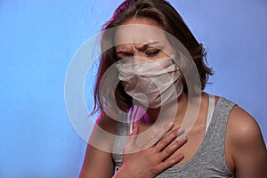 COVID-19 Pandemic Coronavirus. Girl with protective mask on face feels sick, coughs. Woman isolated on the light background