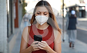 COVID-19 Pandemic Coronavirus Young Woman Wearing KN95 FFP2 Mask Using Smart Phone App in City Street to Aid Contact Tracing