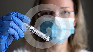 COVID-19 PCR test tube in doctor hand, woman in medical mask holds coronavirus swab collection kit