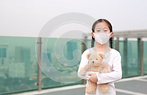 Covid-19 and pollution protection concept. Asian little child girl hugging teddy bear doll with wearing mask to