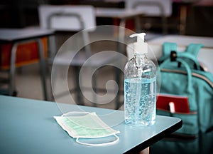 Covid-19 prevention , back to school,new normal concept.Medical face mask and alcohol sanitizer  hand  gel on school desk