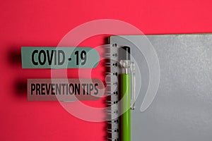 Covid - 19 Prevention Tips write on a sticky note isolated on Office Desk. Healthcare/Medical concept