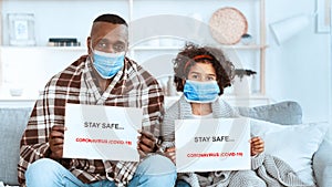 COVID-19 quarantine measures. African American girl with her granddad staying at home wearing protective masks