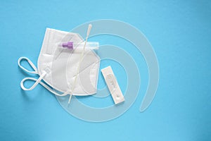 Covid-19 rapid test with negative result, utensils and a medical ffp2 face mask on a light blue background, concept for safety and