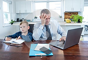 COVID-19 school lockdowns and remote working. Stressed man trying to work from home with bored son