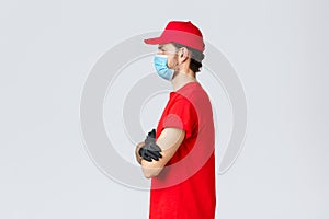 Covid-19, self-quarantine, online shopping and shipping concept. Profile f determined courier in red t-shirt and cap