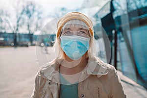 COVID-19 Social Distancing. 50s 60s woman wearing protective face mask against disease virus SARS-CoV-2 outdoors in city